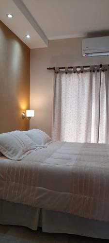 1 dormitorio con cama y ventana con colcha blanca en Chañar y Algarroba en Cafayate