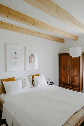 a bedroom with a white bed with a wooden cabinet at Landhaus Schaller im Südburgenland in Maria Bild
