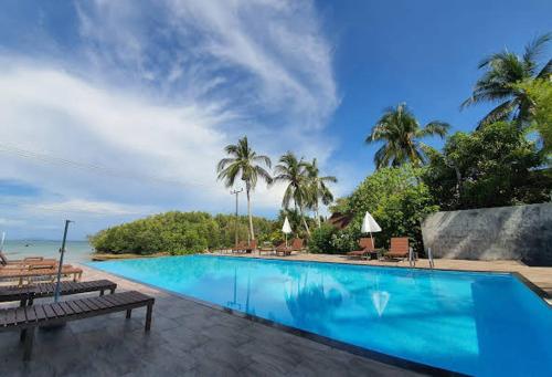 a large swimming pool with palm trees and the ocean at KOHMOOK THE SUN GREAT RESORT in Koh Mook