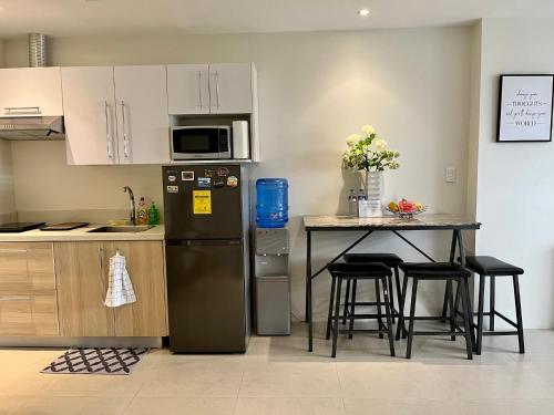 a kitchen with a refrigerator and a table with stools at Elaiza's Cozy Home - Matina Enclaves Building C Unit 815 in Davao City