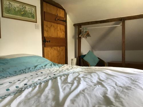 um quarto com uma cama branca e uma porta de madeira em The Coach House em Falkenham