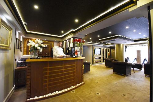 a man standing at a bar in a hotel lobby at Hotel Hymeti's Palace in Pogradec