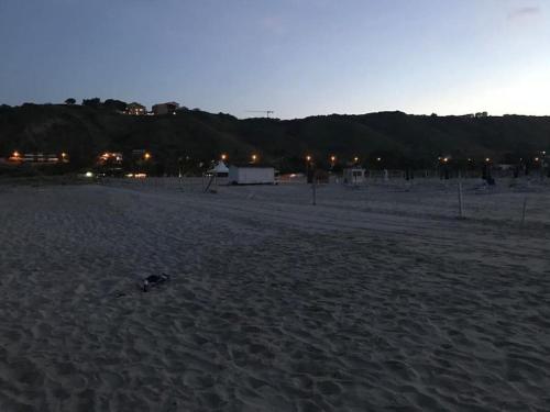 a sandy beach at night with lights in the distance at Il Nido di Mortelle II in Messina