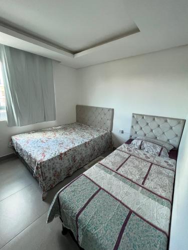 a bedroom with two beds and a window at Apartamento 2 - CARUARU-PE in Caruaru