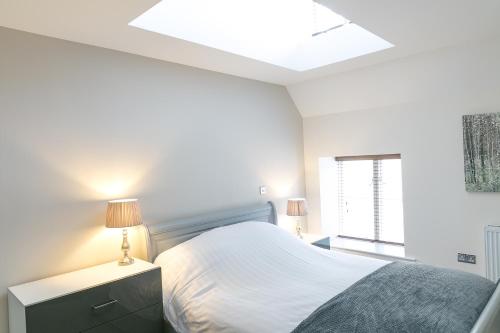 a white bedroom with a bed and a skylight at Riverside Stamford Stays in Stamford