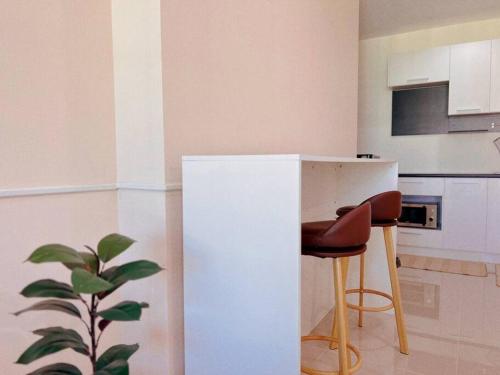 a kitchen with a white counter and two stools at 29th floor Studio, Cozy Workplace, Long stay, wide space in Amphoe Phra Khanong