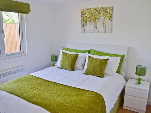 a bedroom with a large white bed with green sheets and pillows at The Cabin in Astley