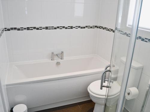 a white bathroom with a tub and a toilet at The Cabin in Astley