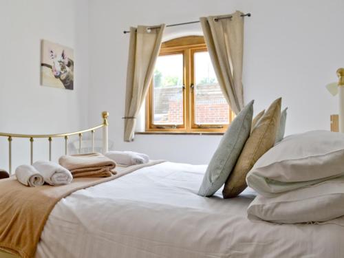 a bedroom with a white bed with pillows and a window at The Chaff House in Arlingham