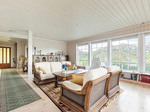 ein Wohnzimmer mit Stühlen, einem Tisch und Fenstern in der Unterkunft Holiday home Kalvåg II in Kalvåg