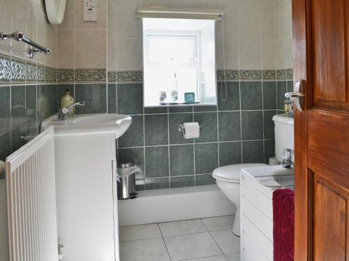 a bathroom with a sink and a toilet and a window at Ffron Erch Cottages - 2712 in Llanarmon