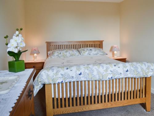 a bedroom with a wooden bed with two lamps at Ffron Erch Cottages - 2712 in Llanarmon