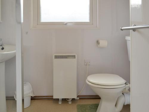 baño blanco con aseo y ventana en The Cottage - B4014 en Wendling