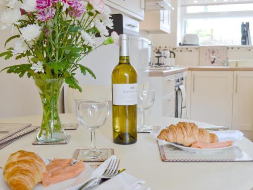 a table with a bottle of wine and a plate of bread at Wren Cottage in Llandeilo