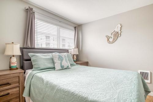 a bedroom with a bed with a green comforter and a window at Whale Watcher Condo #3 in Rockaway Beach