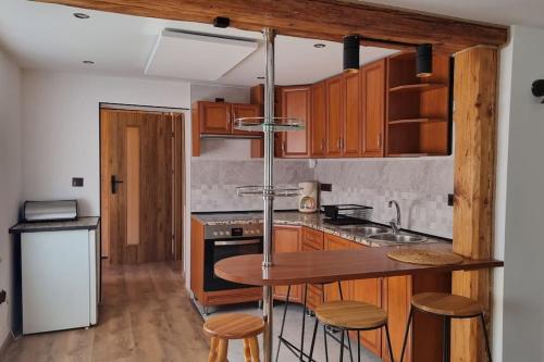 a kitchen with wooden cabinets and a kitchen island with stools at Villa Fantastica Apartments in Mysłakowice