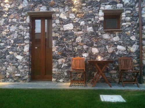 two chairs and a table in front of a stone building at Il Casale Del Giglio in Santo Stefano di Magra