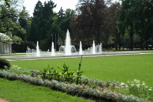 a fountain in a park with green grass and flowers at Lazensky Hotel Park in Poděbrady