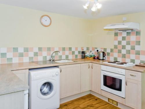 a kitchen with a washing machine and a sink at Anvil Cottage in Blakeney