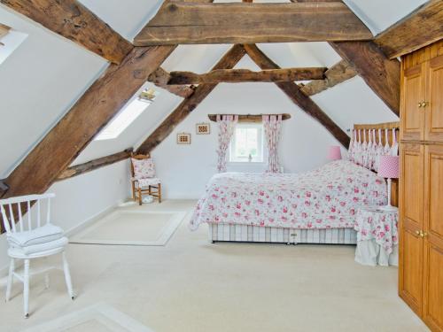 a bedroom in a attic with a bed and a chair at Anvil Cottage in Blakeney