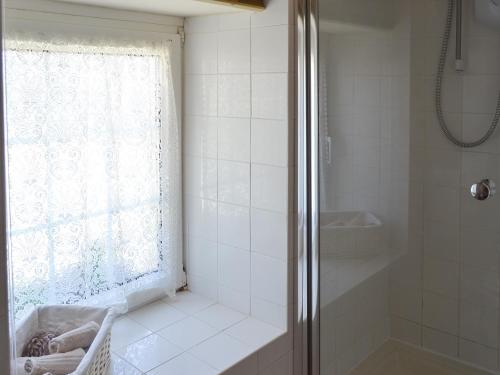 a white bathroom with a shower and a window at Skyber Cottage in Lizard