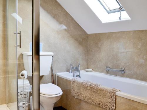 a bathroom with a toilet and a bath tub at Whitehall Pele Tower in Mealsgate