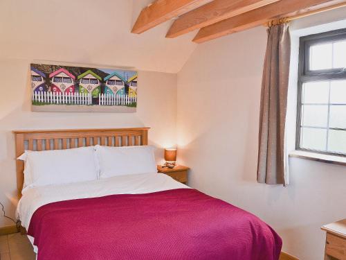 a bedroom with a bed with a red blanket at The Old Stable in Holywell Bay