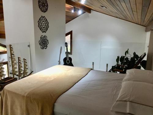um quarto com uma cama com uma guitarra na parede em Casa de campo com piscina em Jaguariaíva