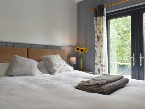 a white bed with a pile of towels on it at Ponsford Ponds Jacks Shepherd Hut - Bcponhut in Cullompton