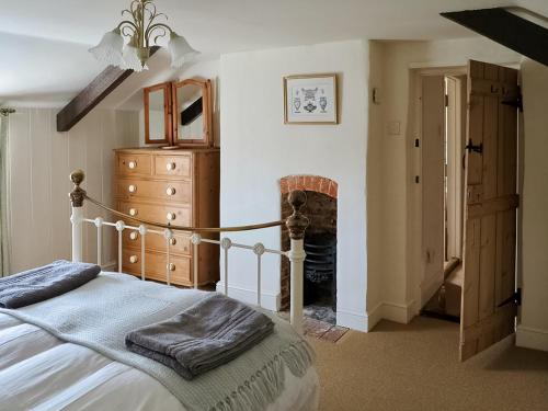 a bedroom with a bed and a dresser and a fireplace at Jennys Cottage 27553 in Mundesley