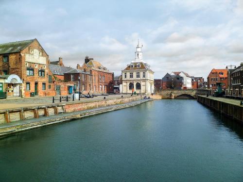 a river in a city with a bridge and buildings at Wagtail Barn in Yaxham