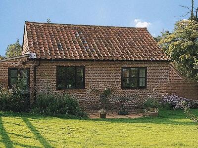 uma pequena casa de tijolos com um jardim de relva em Wagtail Barn em Yaxham