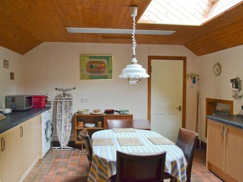 a kitchen with a table with chairs and a ceiling at Dye Mill Cottage in Moffat