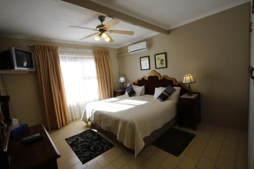 1 dormitorio con 1 cama y ventilador de techo en Bluewater Guesthouse, en Port Elizabeth