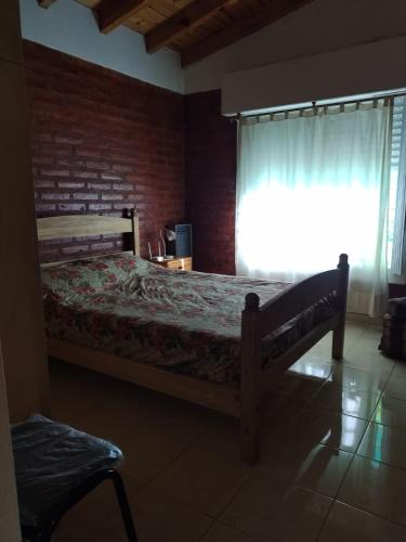 1 dormitorio con cama y ventana con cortina en Casa los delfines en Monte Hermoso