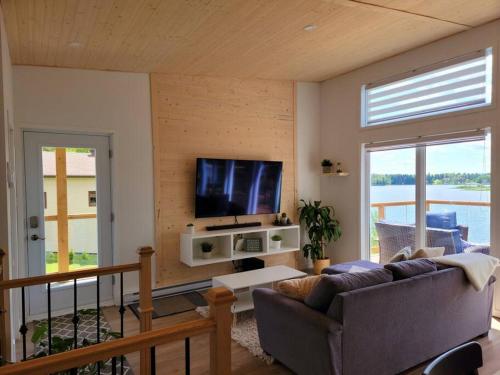 een woonkamer met een bank en een flatscreen-tv bij Au paradis de l'Ashuap in Saint-Félicien