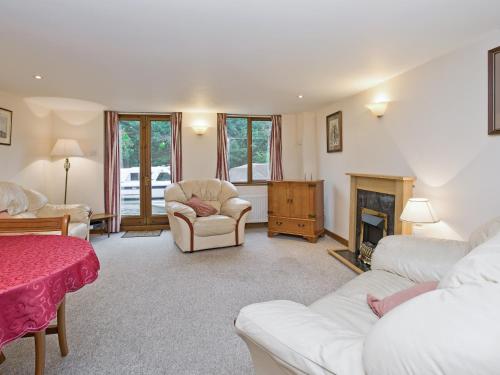 a living room with white furniture and a fireplace at Grebe Cottage in Dilham