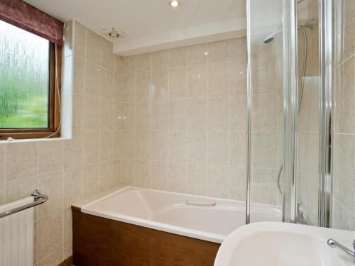 a bathroom with a bath tub and a sink at Grebe Cottage in Dilham