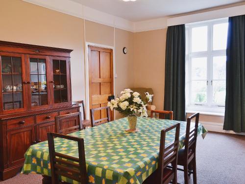 a dining room with a table with a vase of flowers on it at Court Place in Porlock