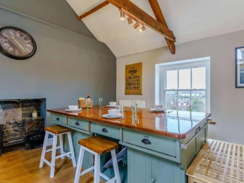 a kitchen with a blue island with a clock on the wall at Yellow Welsh Cottage-Coastal Retreat Village View in Bridgend