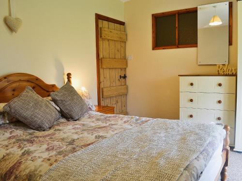 a bedroom with a bed and a dresser and a door at Bodwi Isaf in Llanengan