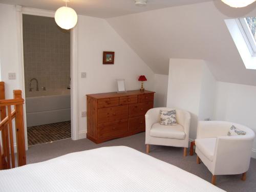 a bedroom with a bed and a chair and a tub at Woodstore Cottage in Lazonby