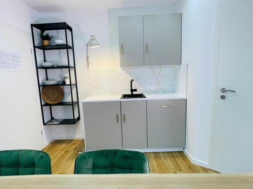 a kitchen with a white cabinet and two green chairs at Stay zentrale Schwarzwald Apartments in Nagold