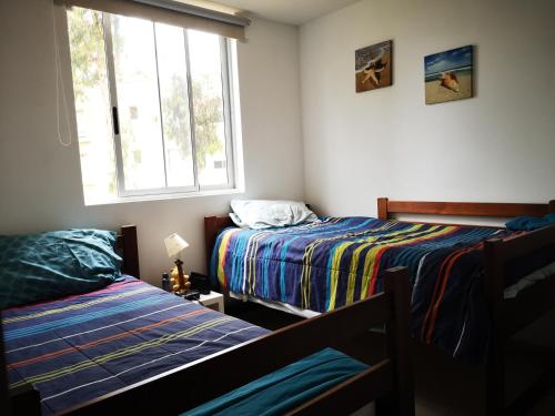 - une chambre avec 2 lits et une fenêtre dans l'établissement Espectacular departamento amoblado en Algarrobo Norte, à San Antonio