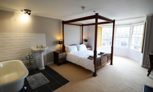 a bedroom with a canopy bed and a sink at Rounceval House in Chipping Sodbury