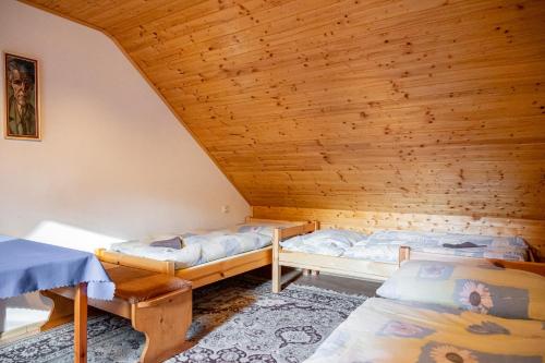 two beds in a room with a wooden ceiling at Penzión DolinkaGápel in Valaská Belá