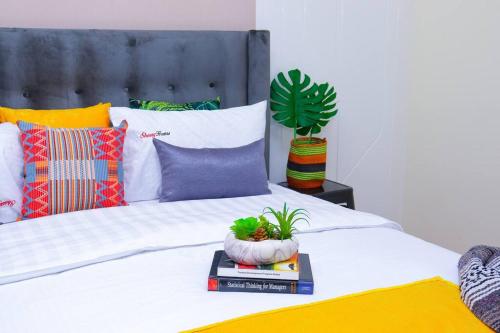 a bedroom with a bed with a plant and books at GTC 1Br Apartment on Westlands Road -with Gym& Pool in Nairobi