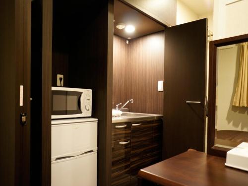 a small kitchen with a microwave and a sink at HOTEL LiVEMAX Himeji Ekimae in Himeji