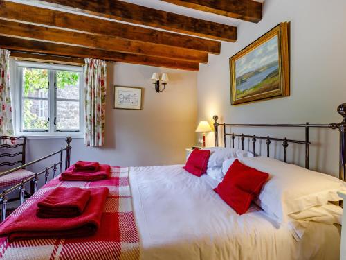 a bedroom with a bed with red pillows on it at Leat Cottage - 16952 in Bampton