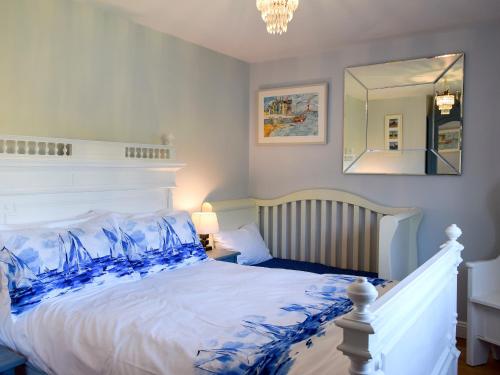 a bedroom with a large white bed with blue pillows at Woodbrook Cottage in Bridport